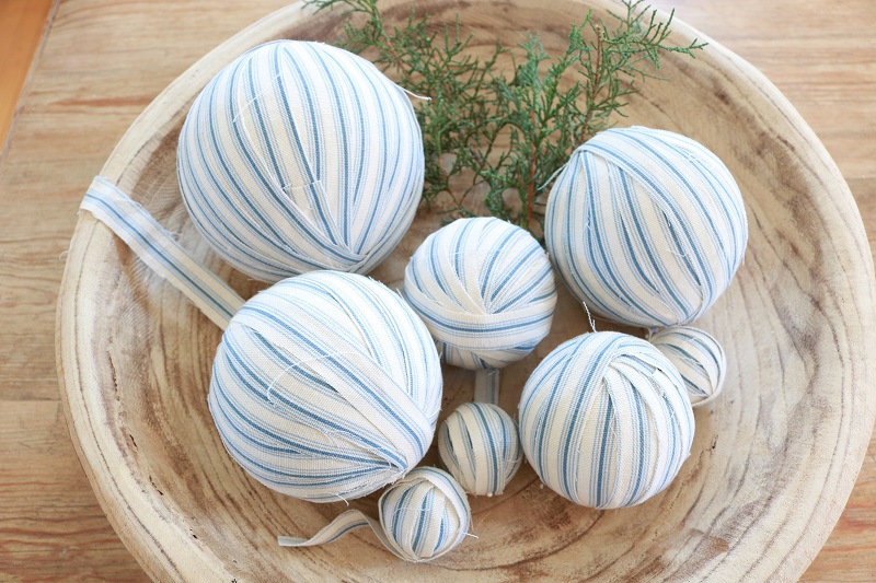 Make these easy DIY ticking stripe Christmas ornaments out of styrofoam balls, ticking fabric and fun embellishments - including wine corks!  #diyornaments #christmasornaments #tickingstripe
