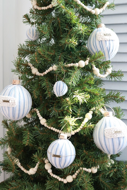 Make these easy DIY ticking stripe Christmas ornaments out of styrofoam balls, ticking fabric and fun embellishments - including wine corks!  #diyornaments #christmasornaments #tickingstripe