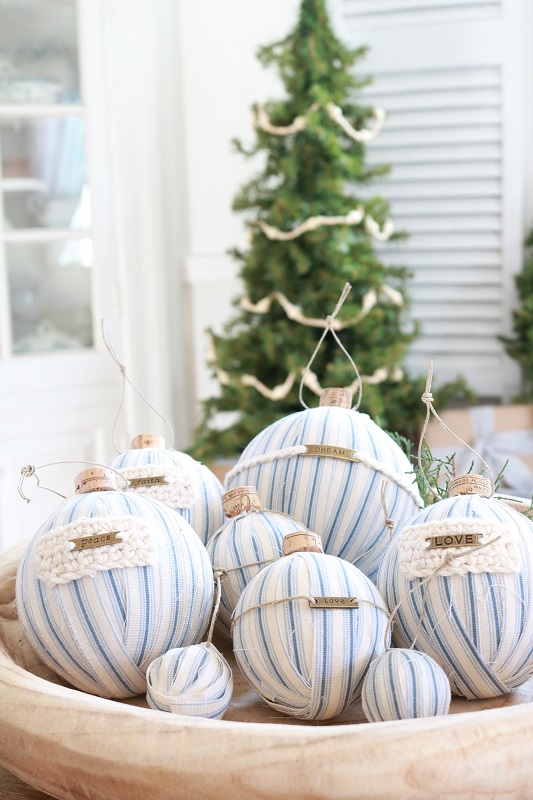 Make these easy DIY ticking stripe Christmas ornaments out of styrofoam balls, ticking fabric and fun embellishments - including wine corks! #diyornaments #christmasornaments #tickingstripe